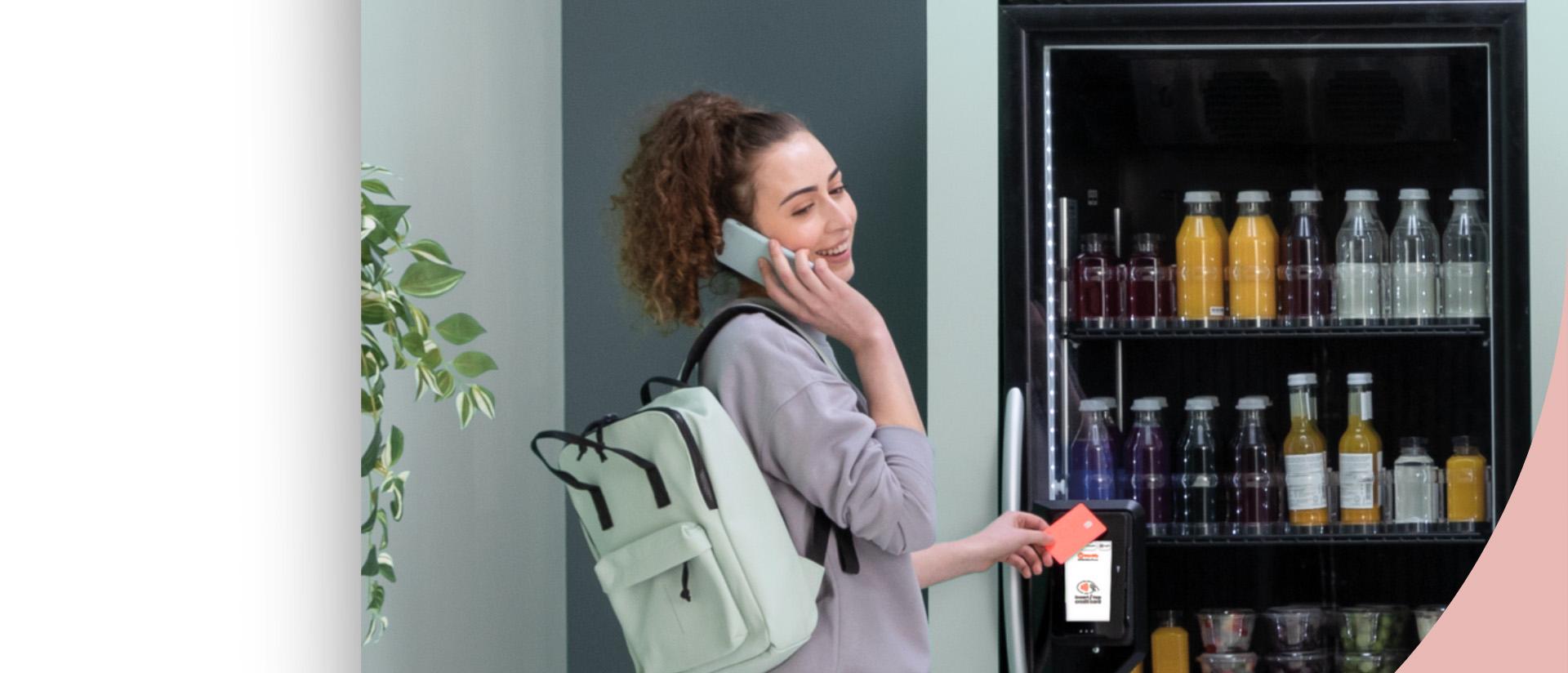 Customer using the payment reader beside a smart cooler